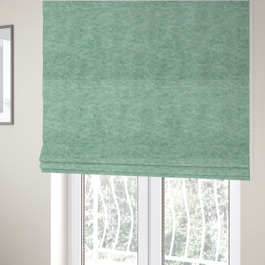 The fabric used to create these Roman blinds is a seafoam or sage green fabric with a rich, distressed felt-like texture. The material features a vibrant yet soft mottled pattern of mint green and pale cream fibres. It is characterized by the signature irregular, light-coloured "crackle" lines found in this collection, giving it the weathered appearance of premium suede or industrial wool.