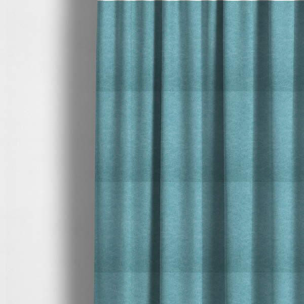 The fabric used to create these made-to-measure curtains is a bright aqua or turquoise fabric with a dense, distressed felt-like texture. The surface features a vibrant mottled pattern of cyan and pale blue fibres, creating a weathered effect. It is characterized by irregular, light-coloured "crackle" lines that give it the weathered appearance of premium suede or industrial wool.