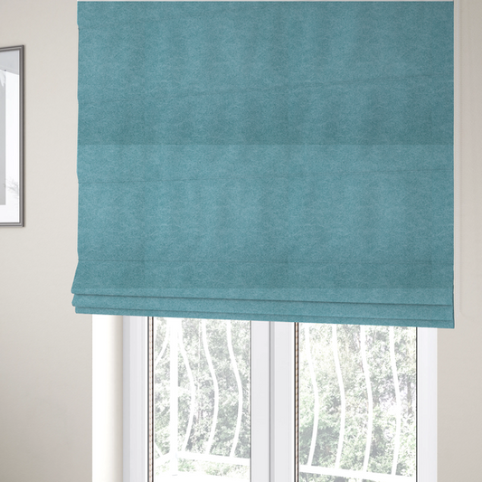 The fabric used to create these Roman blinds is a bright aqua or turquoise fabric with a dense, distressed felt-like texture. The surface features a vibrant mottled pattern of cyan and pale blue fibres, creating a weathered effect. It is characterized by irregular, light-coloured "crackle" lines that give it the weathered appearance of premium suede or industrial wool.