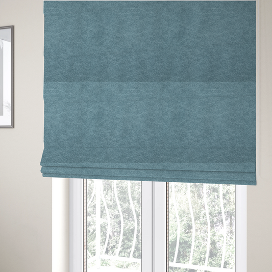 The fabric used to create these Roman blinds is a  dusty blue or slate blue fabric with a dense, distressed felt-like texture. The material features a sophisticated mottled pattern of medium blue and muted grey fibres. It contains the signature irregular, light-coloured "crackle" veins characteristic of this collection, giving it the weathered appearance of premium distressed suede or industrial wool.