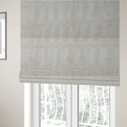 The fabric used to create these Roman blinds is a  pale greige or parchment-coloured fabric with a dense, distressed felt-like texture. The surface features a subtle mottled pattern of light cream and soft grey fibres, creating a clean, weathered look. Like the others in this collection, it includes irregular, light-coloured "crackle" lines that give it the weathered appearance of distressed suede or pressed wool.