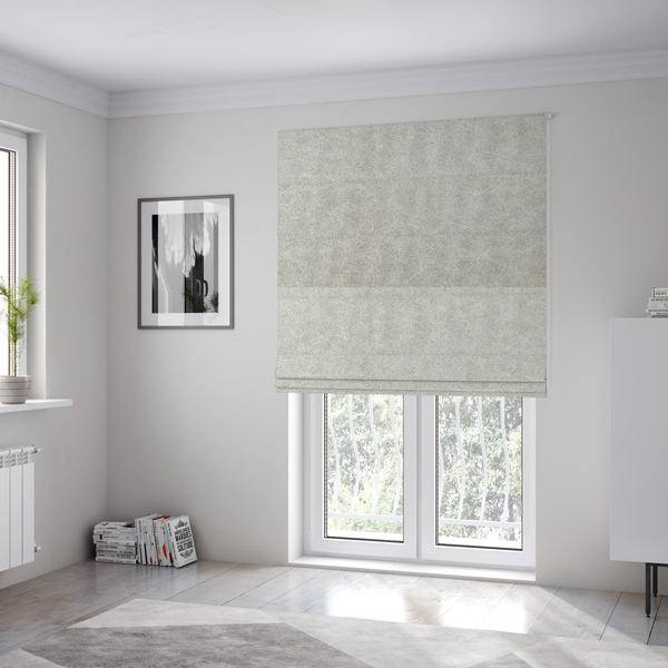 The fabric used to create these Roman blinds is a  pale greige or parchment-coloured fabric with a dense, distressed felt-like texture. The surface features a subtle mottled pattern of light cream and soft grey fibres, creating a clean, weathered look. Like the others in this collection, it includes irregular, light-coloured "crackle" lines that give it the weathered appearance of distressed suede or pressed wool.