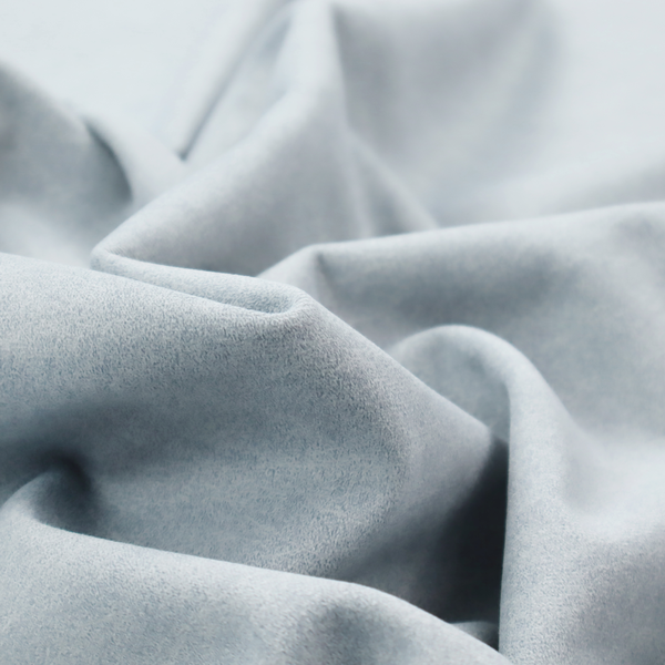 A light sky blue or powder blue fabric with a dense, distressed felt-like texture. The surface features a soft, mottled blend of pale blue and white fibres, creating a subtle weathered effect. It includes the signature irregular, light-coloured "crackle" lines seen throughout this collection, giving it the appearance of weathered microfiber or industrial wool.
