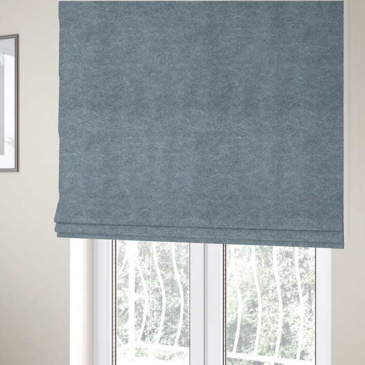 The fabric used to create these Roman blinds is a steel blue or denim grey fabric with a dense, distressed felt-like texture. The material features a sophisticated mottled blend of medium blue and grey fibres, creating a cool-toned weathered effect. It includes the collection’s signature irregular, light-coloured "crackle" lines that give it the weathered appearance of premium distressed suede or industrial wool.