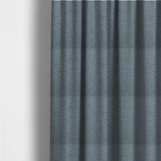 The fabric used to create these made-to-measure curtains is a denim or dusty blue fabric with a dense, distressed felt-like texture. The surface features an intricate mottled blend of slate blue and muted grey fibres. Like the others in this collection, it is defined by organic, light-coloured "crackle" lines and a stippled appearance that mimics the look of weathered suede or high-end industrial wool.