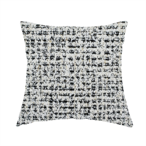 The fabric used to create this handmade cushion is a dense textile with a complex, gridded texture. The fabric is composed of thick white and black yarns interwoven to create a "static" or pixelated marl effect. The weave is highly tactile, showing visible loops, knots, and characteristic of bouclé or tweed. While the overall appearance is monochromatic grey from a distance, the close-up reveals distinct, irregular blocks of stark white and deep black thread.