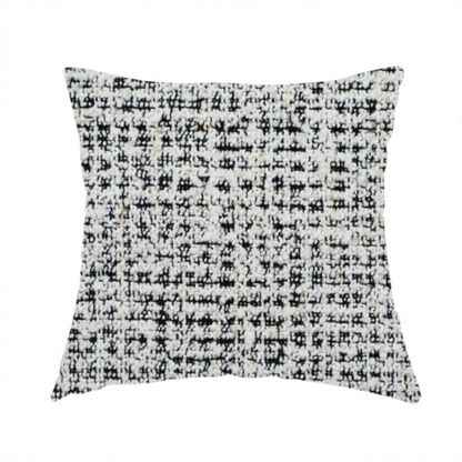 The fabric used to create this handmade cushion is a dense textile with a complex, gridded texture. The fabric is composed of thick white and black yarns interwoven to create a "static" or pixelated marl effect. The weave is highly tactile, showing visible loops, knots, and characteristic of bouclé or tweed. While the overall appearance is monochromatic grey from a distance, the close-up reveals distinct, irregular blocks of stark white and deep black thread.