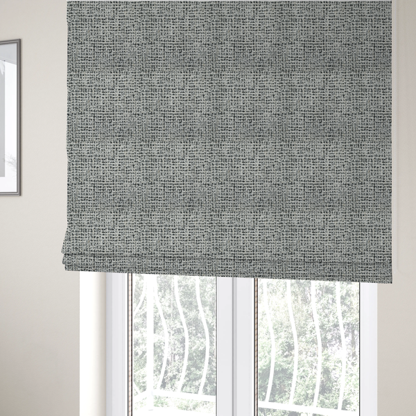 The fabric used to create these Roman blinds is a dense textile with a complex, gridded texture. The fabric is composed of thick white and black yarns interwoven to create a "static" or pixelated marl effect. The weave is highly tactile, showing visible loops, knots, and characteristic of bouclé or tweed. While the overall appearance is monochromatic grey from a distance, the close-up reveals distinct, irregular blocks of stark white and deep black thread.