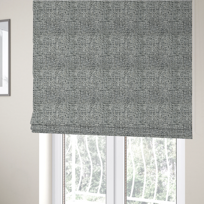 The fabric used to create these Roman blinds is a dense textile with a complex, gridded texture. The fabric is composed of thick white and black yarns interwoven to create a "static" or pixelated marl effect. The weave is highly tactile, showing visible loops, knots, and characteristic of bouclé or tweed. While the overall appearance is monochromatic grey from a distance, the close-up reveals distinct, irregular blocks of stark white and deep black thread.