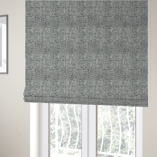 The fabric used to create these Roman blinds is a dense textile with a complex, gridded texture. The fabric is composed of thick white and black yarns interwoven to create a "static" or pixelated marl effect. The weave is highly tactile, showing visible loops, knots, and characteristic of bouclé or tweed. While the overall appearance is monochromatic grey from a distance, the close-up reveals distinct, irregular blocks of stark white and deep black thread.