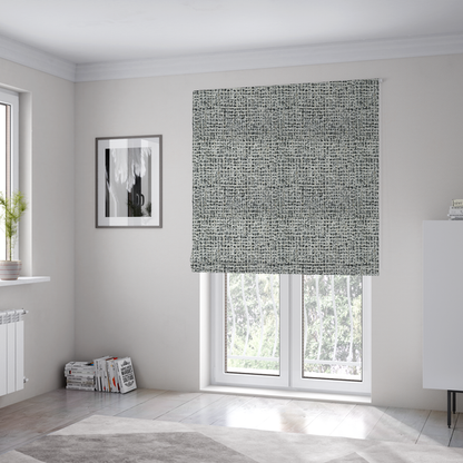 The fabric used to create these Roman blinds is a dense textile with a complex, gridded texture. The fabric is composed of thick white and black yarns interwoven to create a "static" or pixelated marl effect. The weave is highly tactile, showing visible loops, knots, and characteristic of bouclé or tweed. While the overall appearance is monochromatic grey from a distance, the close-up reveals distinct, irregular blocks of stark white and deep black thread.