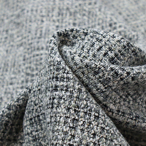A dense, textured woven fabric in a charcoal and ash-grey salt-and-pepper pattern. The weave features tightly packed, nubby bouclé yarns with a subtle vertical and horizontal grid-like structure.