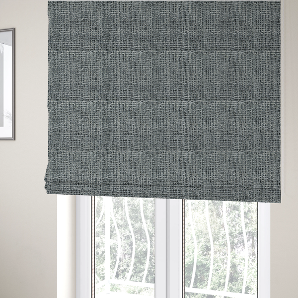 The fabric used to create these Roman blinds is a dense, textured woven fabric in a charcoal and ash-grey salt-and-pepper pattern. The weave features tightly packed, nubby bouclé yarns with a subtle vertical and horizontal grid-like structure.