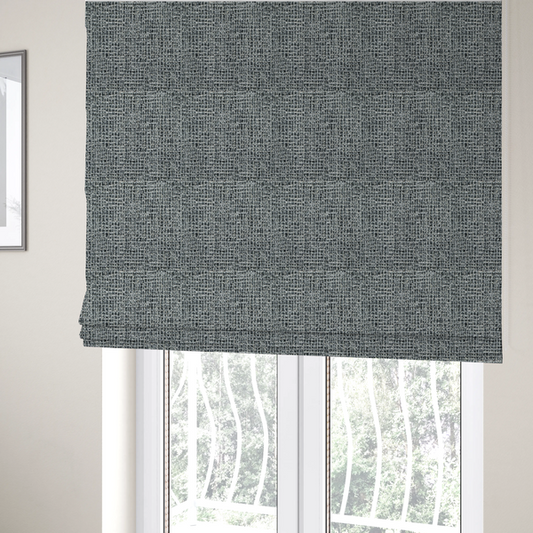 The fabric used to create these Roman blinds is a dense, textured woven fabric in a charcoal and ash-grey salt-and-pepper pattern. The weave features tightly packed, nubby bouclé yarns with a subtle vertical and horizontal grid-like structure.