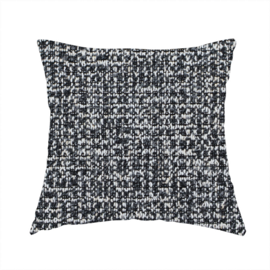 The fabric used to create this handmade cushion is a dark, heavyweight woven fabric with a charcoal and slate-grey salt-and-pepper pattern. The dense bouclé weave creates a highly textured, pebbled surface with subtle off-white specks.
