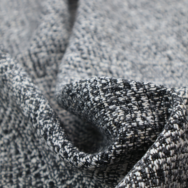 A dark, heavyweight woven fabric with a charcoal and slate-grey salt-and-pepper pattern. The dense bouclé weave creates a highly textured, pebbled surface with subtle off-white specks.