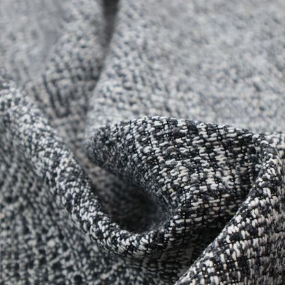 A dark, heavyweight woven fabric with a charcoal and slate-grey salt-and-pepper pattern. The dense bouclé weave creates a highly textured, pebbled surface with subtle off-white specks.