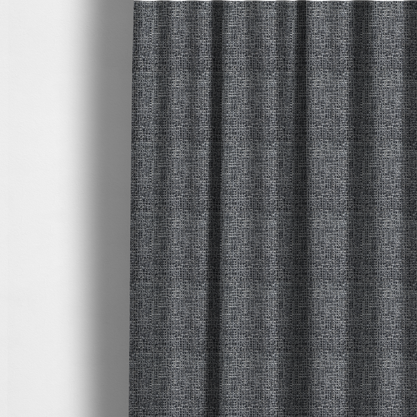 The fabric used to create these made-to-measure curtains is a dark, heavyweight woven fabric with a charcoal and slate-grey salt-and-pepper pattern. The dense bouclé weave creates a highly textured, pebbled surface with subtle off-white specks.