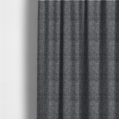 The fabric used to create these made-to-measure curtains is a dark, heavyweight woven fabric with a charcoal and slate-grey salt-and-pepper pattern. The dense bouclé weave creates a highly textured, pebbled surface with subtle off-white specks.
