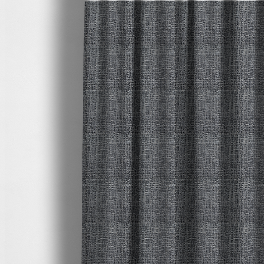 The fabric used to create these made-to-measure curtains is a dark, heavyweight woven fabric with a charcoal and slate-grey salt-and-pepper pattern. The dense bouclé weave creates a highly textured, pebbled surface with subtle off-white specks.