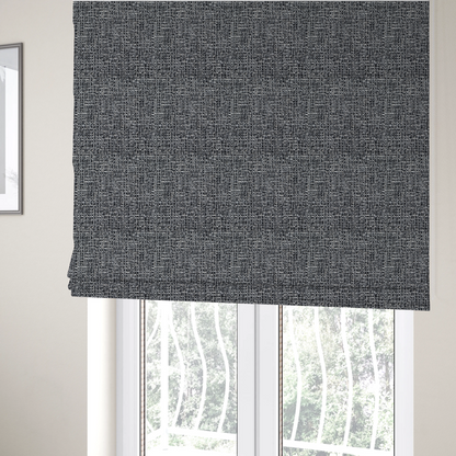 The fabric used to create these Roman blinds is a dark, heavyweight woven fabric with a charcoal and slate-grey salt-and-pepper pattern. The dense bouclé weave creates a highly textured, pebbled surface with subtle off-white specks.