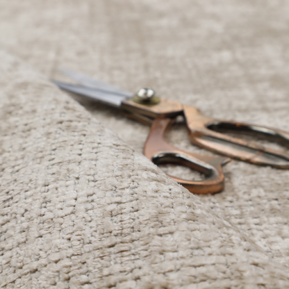 A beige and sand-toned upholstery fabric. The material features a chunky, multi-layered boucle texture with a prominent architectural grid pattern and a mix of warm tan and ivory yarns.