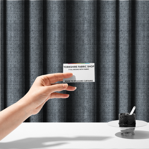 The fabric used to create these made-to-measure curtains is a slate blue and grey textured boucle fabric with a dense, dimensional grid weave.