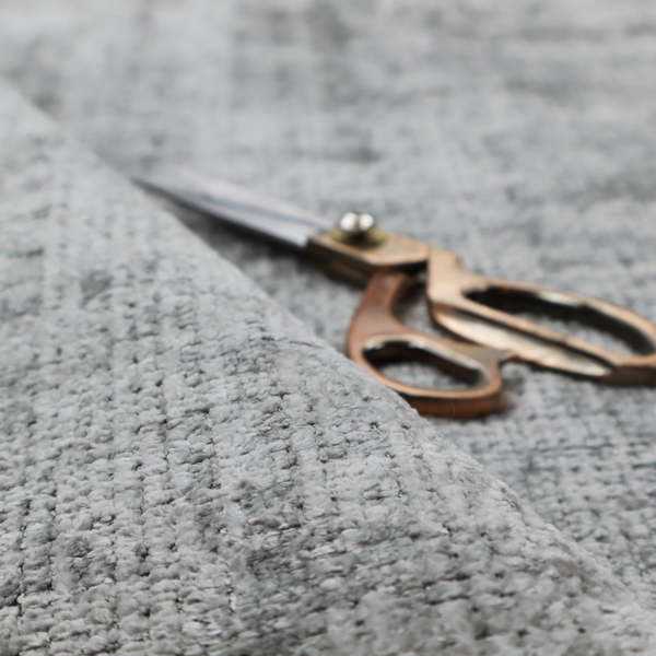 A silver-grey textured boucle fabric with a dimensional grid weave and mottled grey accents.