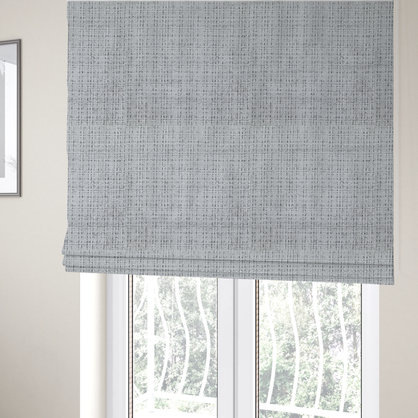 The fabric used to create these Roman blinds is a light grey upholstery fabric. This material features a dense boucle texture with a prominent architectural grid pattern. The weave combines pale grey and charcoal-flecked yarns, creating a sophisticated, salt-and-pepper dimensional effect.