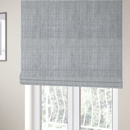 The fabric used to create these Roman blinds is a light grey upholstery fabric. This material features a dense boucle texture with a prominent architectural grid pattern. The weave combines pale grey and charcoal-flecked yarns, creating a sophisticated, salt-and-pepper dimensional effect.