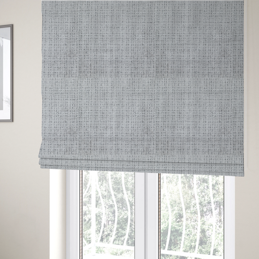 The fabric used to create these Roman blinds is a light grey upholstery fabric. This material features a dense boucle texture with a prominent architectural grid pattern. The weave combines pale grey and charcoal-flecked yarns, creating a sophisticated, salt-and-pepper dimensional effect.