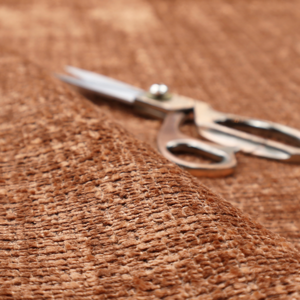 Scanno Weave upholstery fabric in a warm tan shade, showcasing a detailed, woven texture with an interlocking grid pattern.