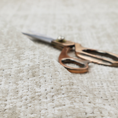 Scanno Weave upholstery fabric in a creamy off-white shade, featuring a detailed, woven texture with an interlocking grid pattern.