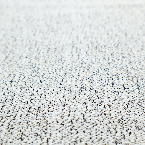 A textured white fabric with an intricate, irregular black speckled pattern throughout.