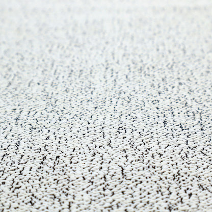 A textured white fabric with an intricate, irregular black speckled pattern throughout.