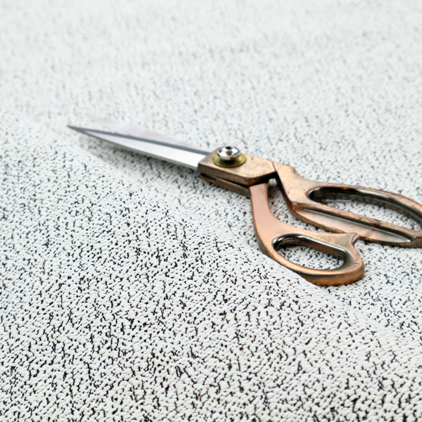 A textured white fabric with an intricate, irregular black speckled pattern throughout.