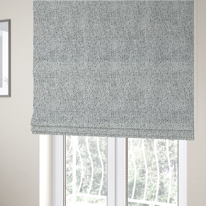 The fabric used to create these Roman blinds is a textured white fabric with an intricate, irregular black speckled pattern throughout.