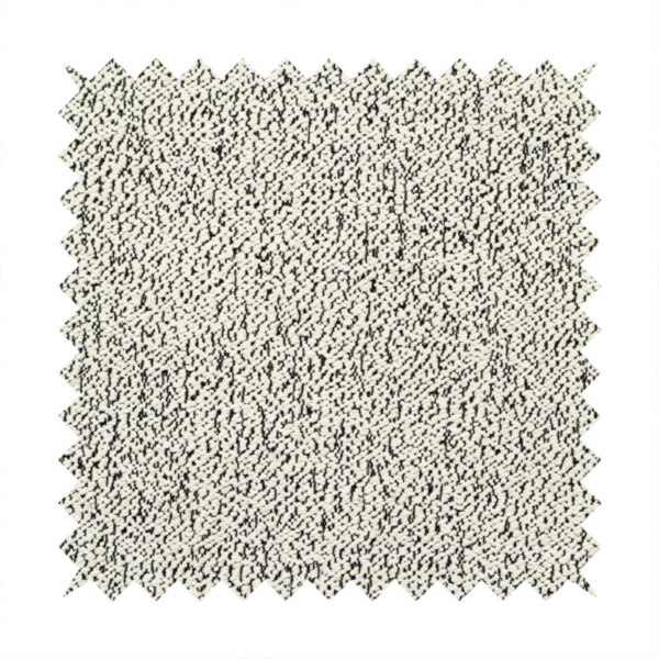 A cream-coloured textured fabric with a dense, irregular black speckled pattern.