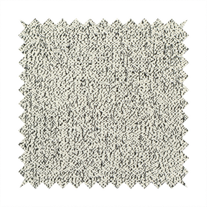 A cream-coloured textured fabric with a dense, irregular black speckled pattern.