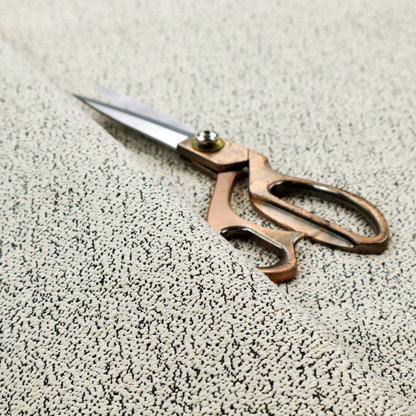 A cream-coloured textured fabric with a dense, irregular black speckled pattern.