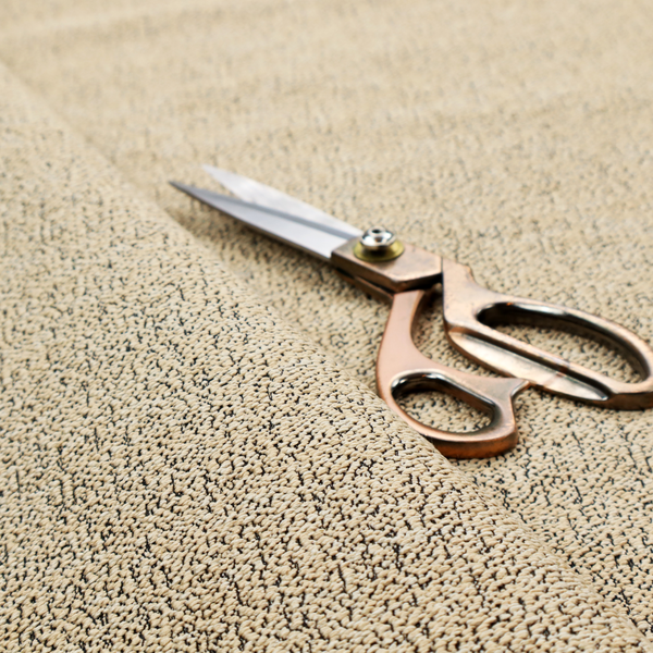 A beige textured fabric with a dense, irregular black speckled pattern.