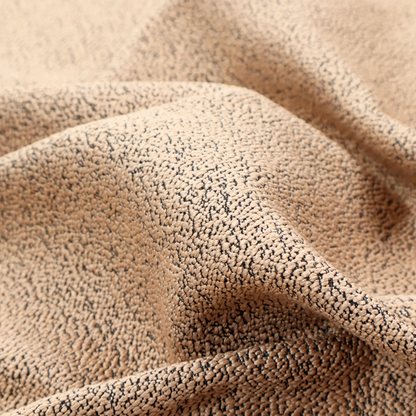 A tan textured fabric with a dense, irregular black speckled pattern.