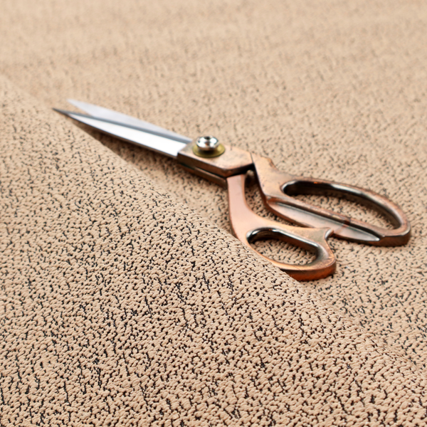 A tan textured fabric with a dense, irregular black speckled pattern.