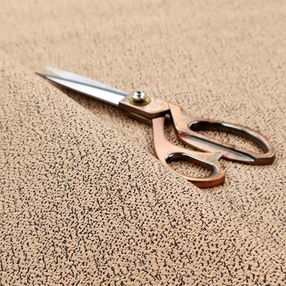 A tan textured fabric with a dense, irregular black speckled pattern.