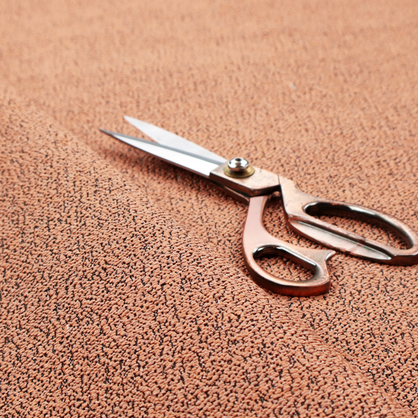 A terracotta orange textured fabric with a dense, irregular black speckled pattern.