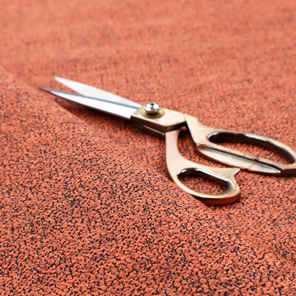 A coral textured fabric with a dense, irregular black speckled pattern.