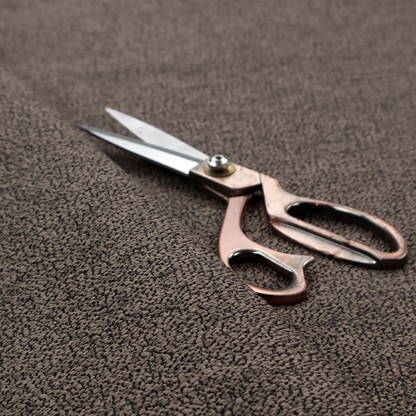 A dark brown textured fabric with a dense, irregular black speckled pattern.