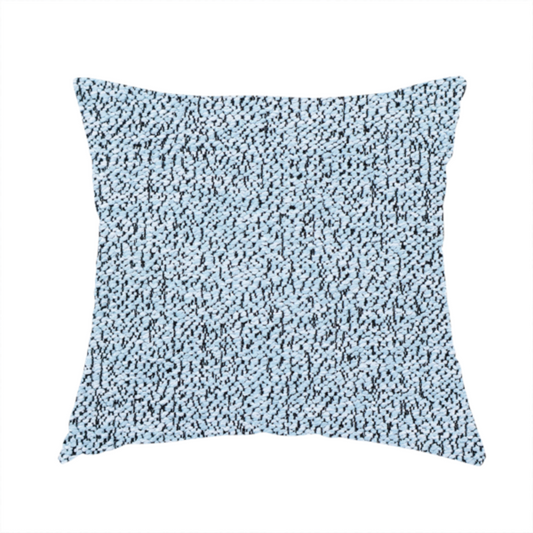 The fabric used to create this handmade cushion is a light blue textured fabric with a dense, irregular black speckled pattern.