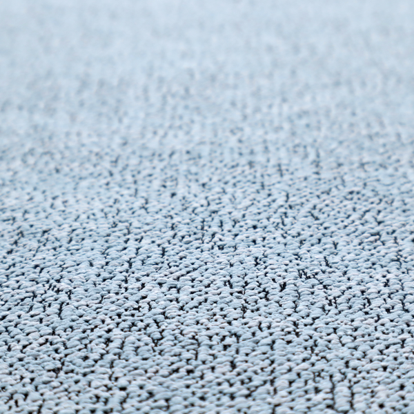 A light blue textured fabric with a dense, irregular black speckled pattern.