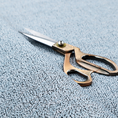 A light blue textured fabric with a dense, irregular black speckled pattern.